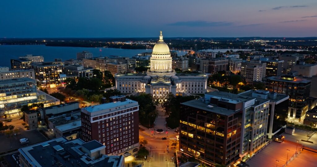 Capitol building at night with surrounding city lights.