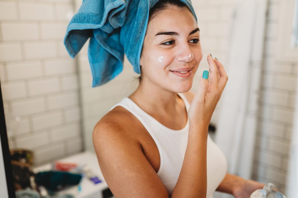 Woman applying skin cream after shower