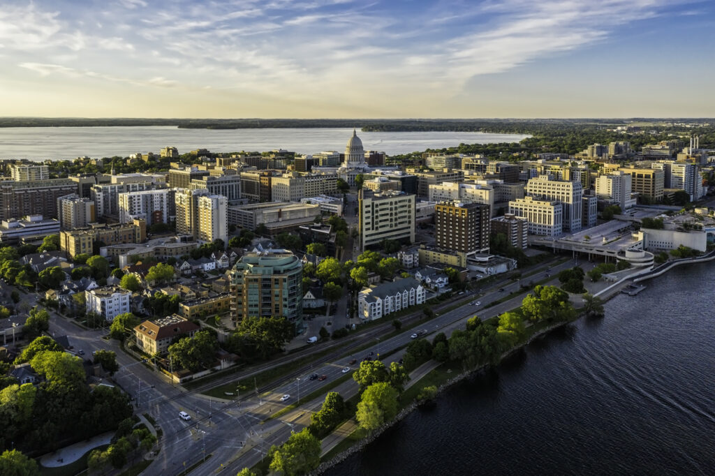 Aerial view of cityscape with lake and capitol building.