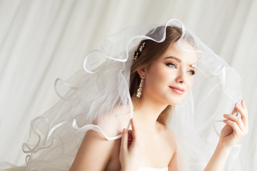 Bride smiling under delicate white wedding veil