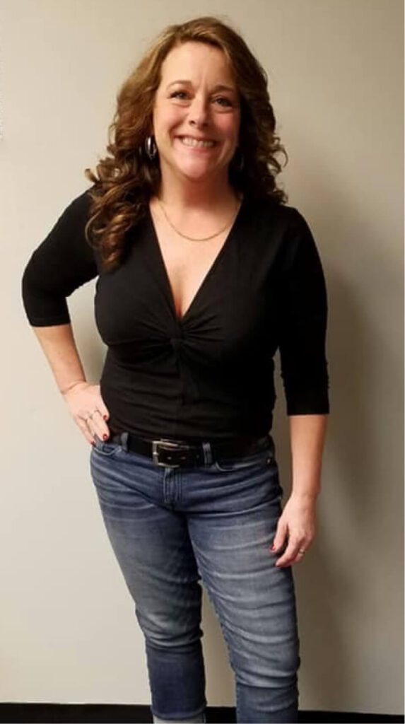 Smiling woman in a black shirt and jeans.